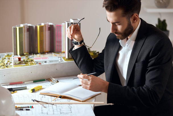 young bearded good looking skilled architect making notes on his notepad - 写真・画像