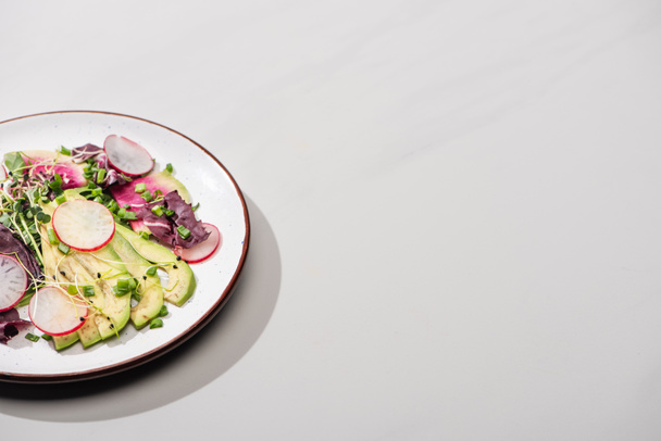 verse radijssalade met groenten en avocado op grijze ondergrond - Foto, afbeelding