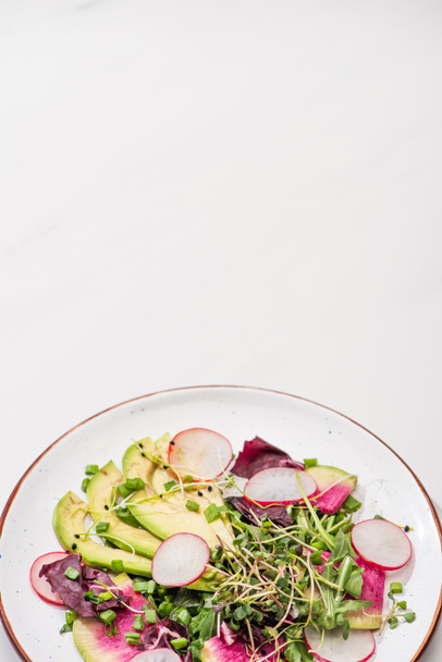 fresh radish salad with greens and avocado on plate on white surface - Fotoğraf, Görsel