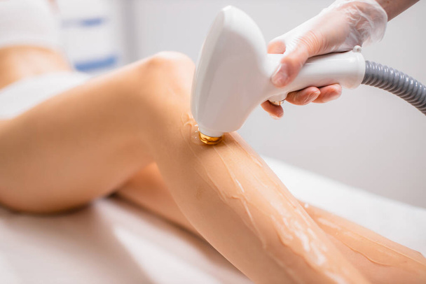 close-up womans legs while getting hair removal procedure in salon - Fotó, kép