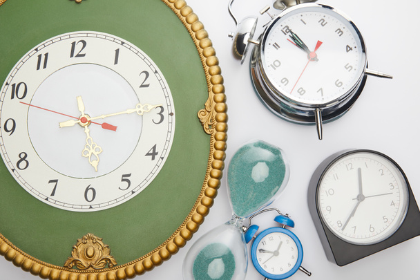 vista superior de los relojes de alarma clásicos y reloj de arena sobre fondo blanco
 - Foto, imagen