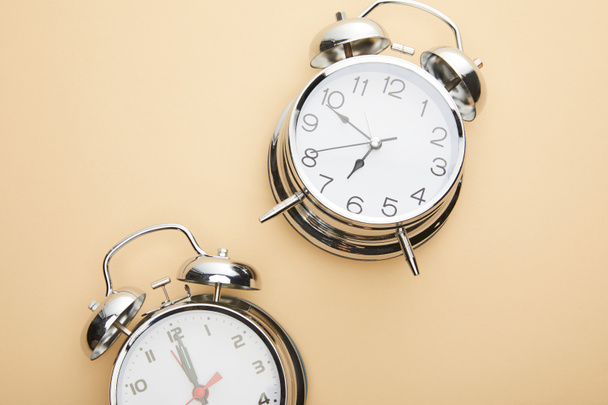 top view of classic alarm clocks on beige background - Foto, afbeelding