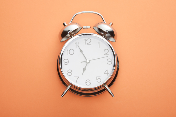 top view of classic alarm clock on peach background - Foto, afbeelding