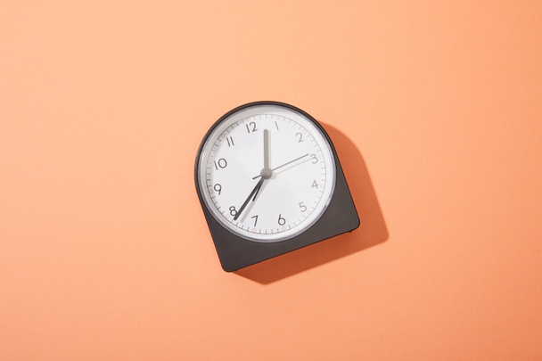 top view of clock on peach background - 写真・画像