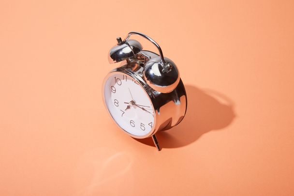 reloj despertador clásico sobre fondo melocotón
 - Foto, imagen