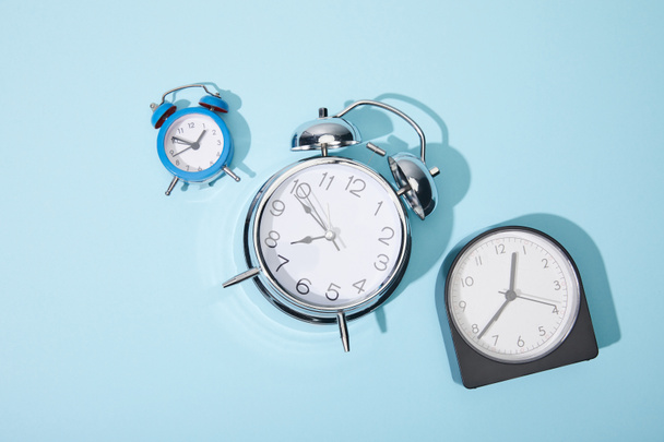 top view of alarm clocks on blue background - Foto, afbeelding