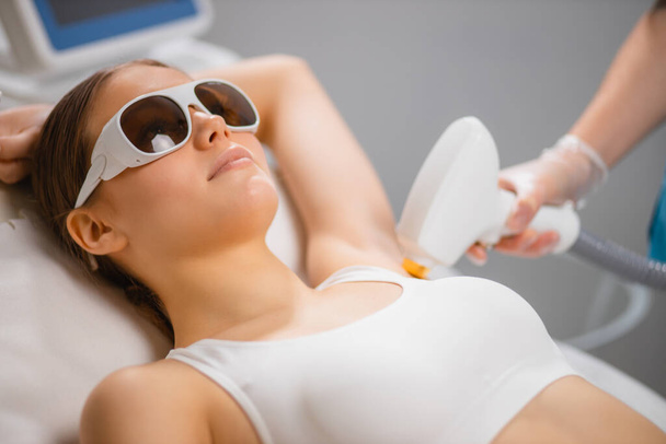 young lady getting laser epilation procedure on armpits - Foto, afbeelding