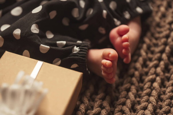 Um bebê recém-nascido e caixas com presentes. Pés do bebê recém-nascido e presentes de Natal. Uma criança é o presente mais desejável - Fotografia, imagem