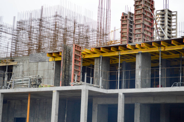 Het proces van de bouw en reparatie van een nieuwe moderne cement beton pannel monolithische frame-block bouw van een huis met ijzer versterking op een industriële bouwplaats - Foto, afbeelding