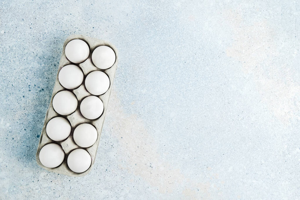 Box with white eggs on blue background. Flatlay, copy space - Foto, afbeelding