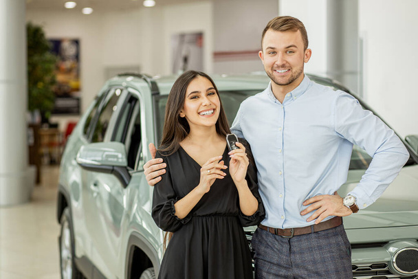 Porträt eines schönen jungen lächelnden Paares, das den Schlüssel zu seinem neuen Auto, dem Auto, in der Hand hält - Foto, Bild