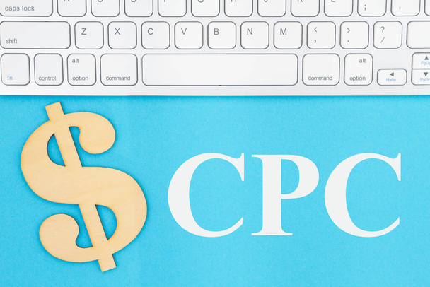 CPC Coste por clic mensaje con teclado gris con un signo de dólar en un papel azul
 - Foto, imagen