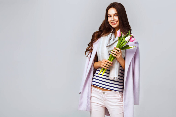 March 8 Fashion photo of a beautiful young woman with tulips in her hand. Spring concept.  - Foto, imagen