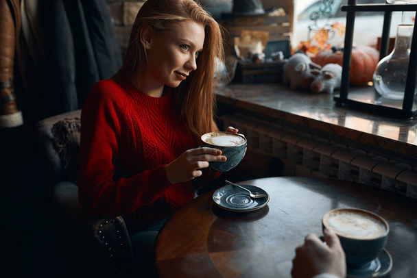 Beautiful girl with blue eyes drinking coffee in restaurant. - Foto, Imagem