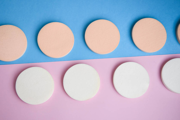 White and beige makeup sponges on the blue and pink background, Close up, Cosmetic sponges powder for face makeup, Cosmetic sponges, Beauty concept - Fotografie, Obrázek