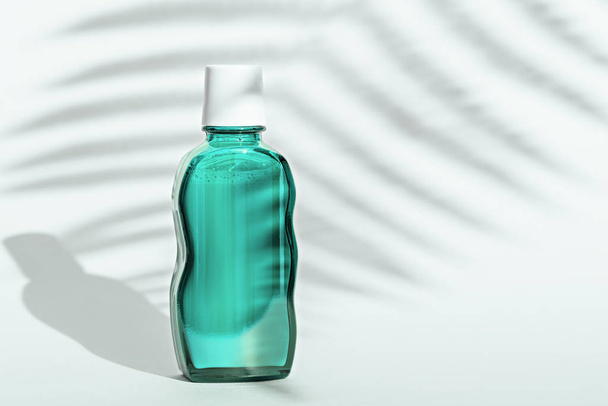 bottiglia di vetro verde con coperchio bianco su sfondo bianco con ombra foglia, spazio copia
 - Foto, immagini