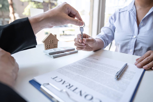 Real estate agent are presenting home loan and giving house, keys to customer after signing contract to buy house with approved property application form. - Photo, Image