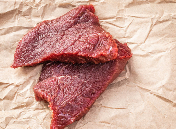 Two raw beef steaks lie on food paper, side view from above - Фото, изображение
