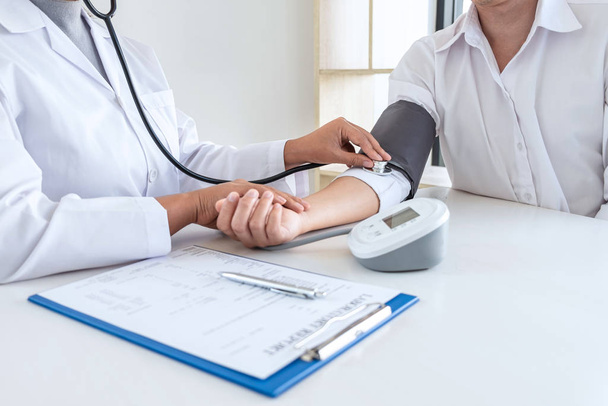Médecin utilisant la vérification stéthoscopique mesurant la pression artérielle sur le bras à un patient à l'hôpital, les soins de santé et le concept médical
. - Photo, image