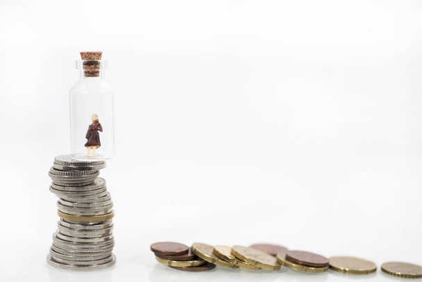 Kleine Frau im Reagenzglas auf Münzen. Abstraktes Foto der Finanzkrise. - Foto, Bild
