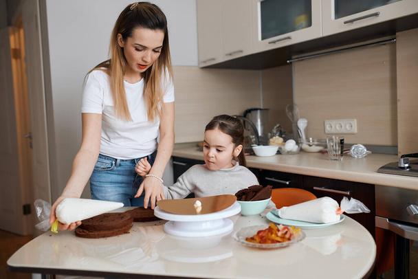 little cute girl and her mother baking cake for daddy - Foto, afbeelding