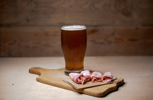 A glass of beer with smoked bacon - Фото, изображение
