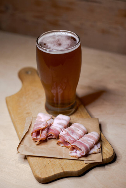 A glass of beer with smoked bacon - Фото, изображение