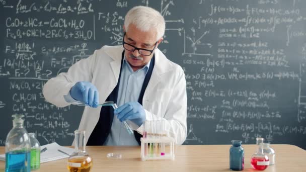 Mature man scientist conducting chemical test in laboratory taking notes - Video