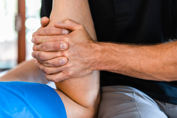 Sports physiotherapist massaging muscular strong man - Фото, изображение