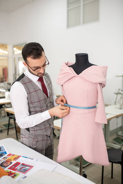 Male tailor measuring waist of dress with measuring tape - Foto, immagini