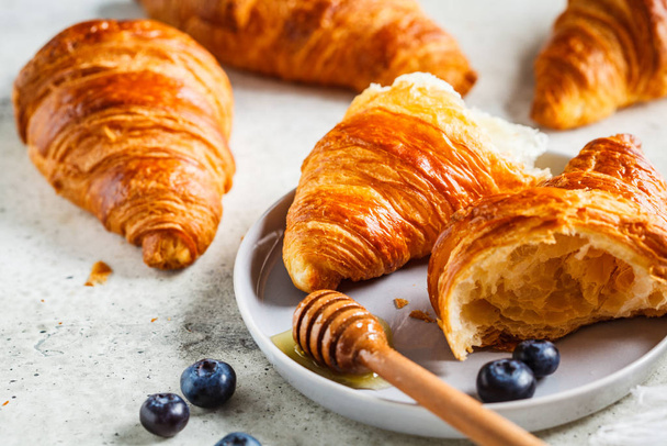 Fresh croissants with blueberries and honey, gray background, copy space. - Zdjęcie, obraz