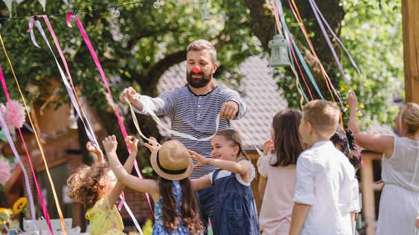 Man with kids on birthday party playing outdoors in garden in summer. - 写真・画像