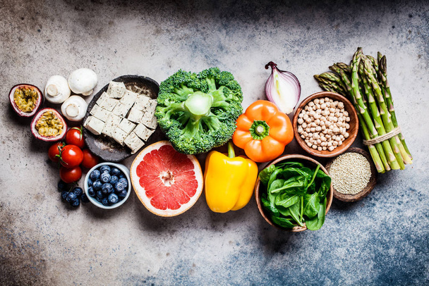Vegan food background. Vegetables, fruits, chickpeas, quinoa, tofu and mushrooms on gray background. - Photo, image