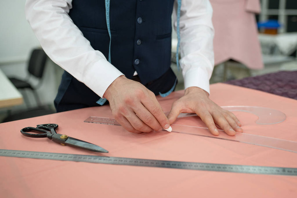 Hands of male tailor outlining pattern on pink cloth - Photo, Image