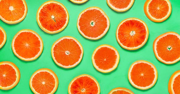Fruit pattern of red grapefruit citrus slices on green background. Top view. - Foto, Bild