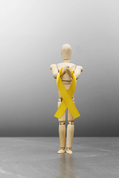Dřevěná panenka drží zlato Dětství rakovina stuha - Fotografie, Obrázek