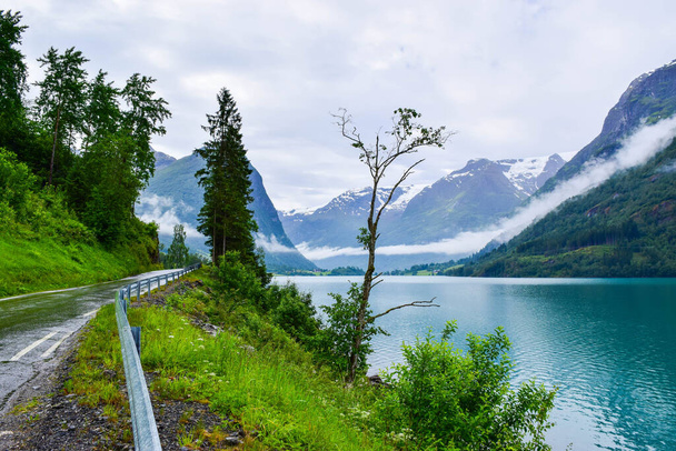 Krajobraz pięknego jeziora polodowcowego Oldevatnet i mglistych gór, w których znajdują się lodowce Parku Narodowego Jostedalsbreen. Norwegia. - Zdjęcie, obraz