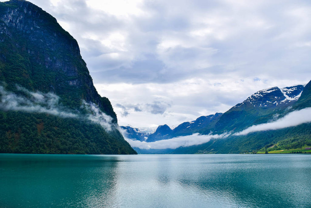Landschaft mit wunderschönem Oldevatnet-Gletschersee und nebligen Bergen, in denen sich Gletscher des Nationalparks Jostedalsbreen befinden. Norwegen. - Foto, Bild