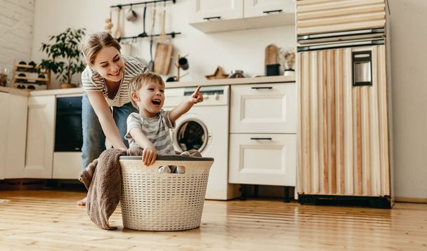 Mère de famille heureuse femme au foyer et enfant fils dans la blanchisserie avec lave-linge
 - Photo, image