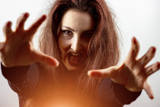 Wütende und verrückte brünette Hexe, die Zauber ausübt und schreit, gruseliger Horror, Hexerei und Halloween-Konzept - Foto, Bild