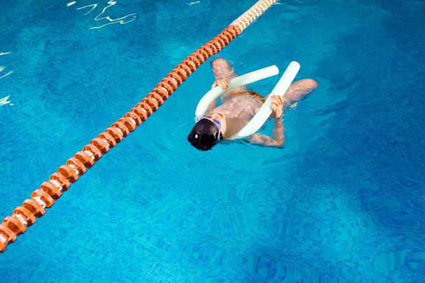 Menino pré-adolescente nadando na piscina interior durante a aula de natação
 - Foto, Imagem