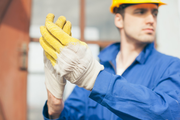 Builder Taking Off Protective Gloves - Foto, Bild