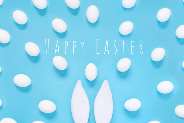 Easter concept. Rabbit ears and white eggs. On a blue background. - Photo, image