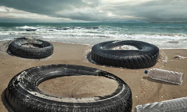 Ελαστικά αυτοκινήτων και πλαστικά μπουκάλια ρύπανσης σε λασπώδη λακκούβα στην παραλία. (Έννοια περιβάλλοντος) - Φωτογραφία, εικόνα