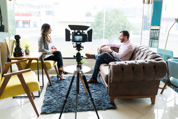 Profissionais masculinos e femininos sentados no sofá durante a gravação da entrevista no escritório
 - Foto, Imagem