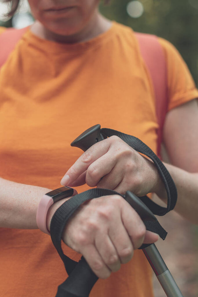 Woman hiker using smart bracelet during trekking in nature. Close up of female hands with portable information device, selective focus. - Fotoğraf, Görsel