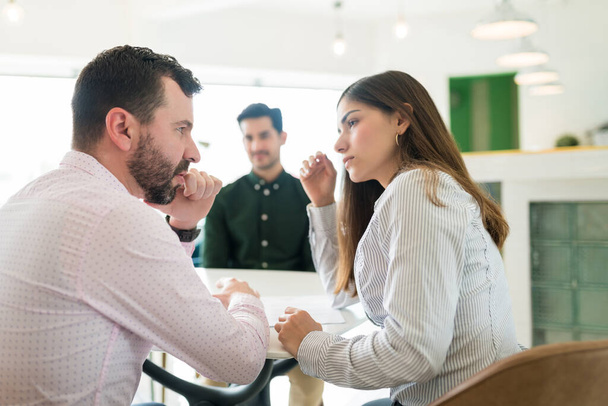 Male and female recruiters discussing while interviewing candidate at workplace - Photo, Image