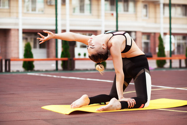 Hermosa mujer deportiva está haciendo ejercicio al aire libre. Yoga asana. pose de camello
 - Foto, imagen