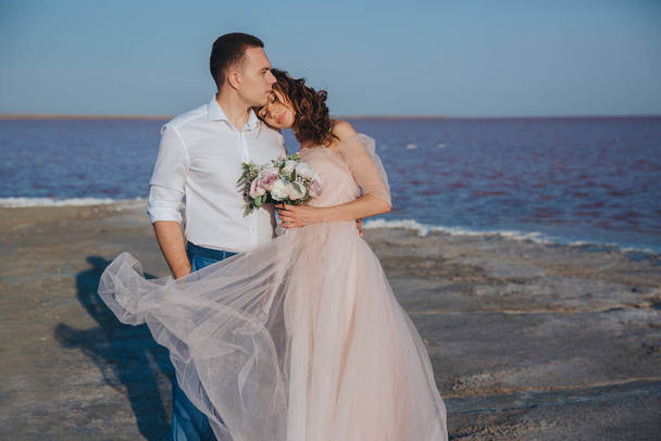 beautiful newlyweds on the sea shore and gentle groom, hugging the bride. front view. - Foto, immagini