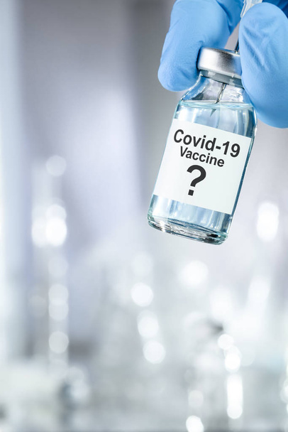 Возможная концепция лечения с рукой в синих медицинских перчатках, содержащих коронавирус, вирус Ковид 19, пузырек с вакциной
 - Фото, изображение
